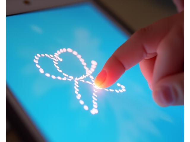 Child tracing lines on a tablet screen, developing fine motor skills.